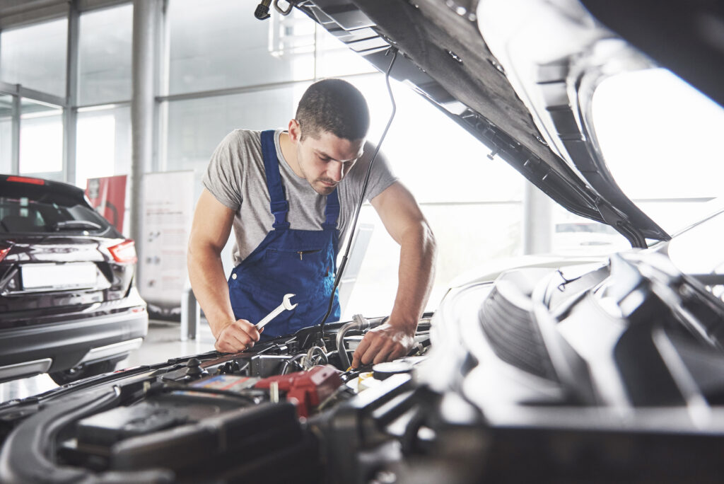 Picture showing muscular car service worker repairing vehicle.